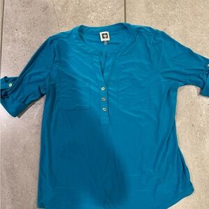 Turquoise knit shirt with v neck and gold button details. Elbow sleeves.